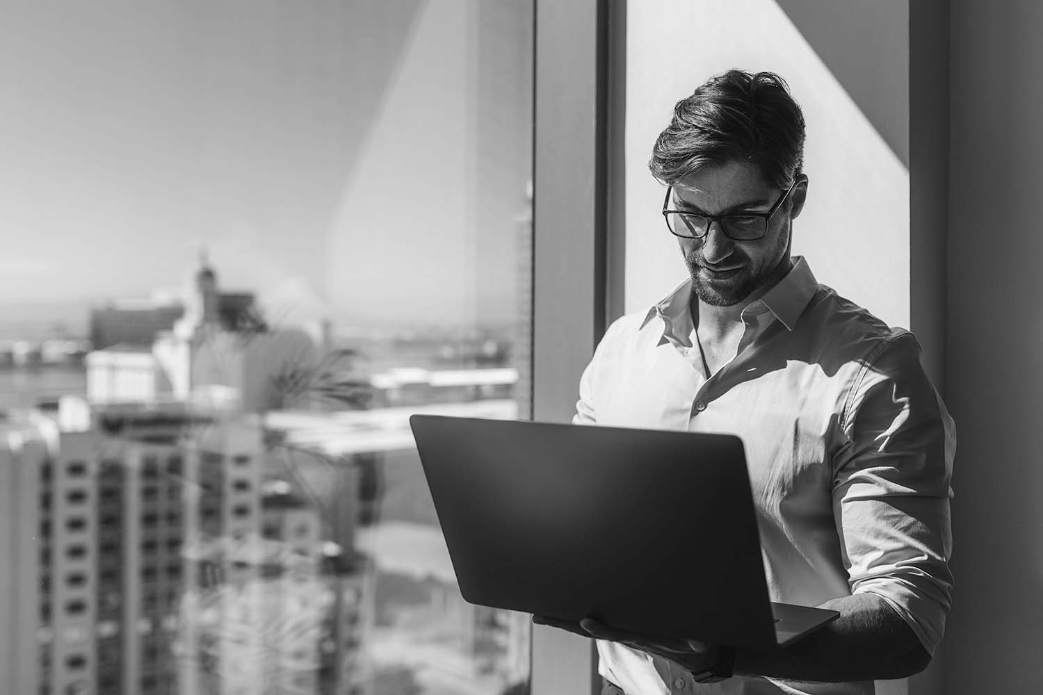 Executive Remuneration: man in glasses working beside office window